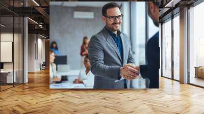 Portrait of cheerful young manager handshake with new employee. Business partnership meeting in office. Close up of handshake in the office. Mature businessman shake hands with a younger colleague Wall mural