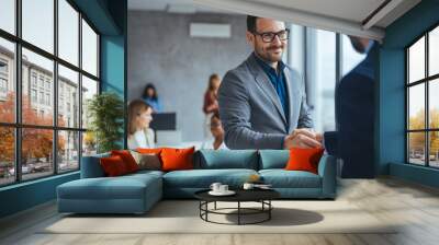 Portrait of cheerful young manager handshake with new employee. Business partnership meeting in office. Close up of handshake in the office. Mature businessman shake hands with a younger colleague Wall mural