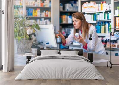 Portrait of pharmacist standing at counter in pharmacy. Pharmacist using the computer at the pharmacy. Medicine, healthcare and technology concept Wall mural