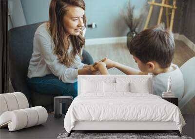 Shot of a little boy talking to a psychologist. Attentive and sympathetic woman psychologist listens to little boy. Notes to himself in clipboard. Mental health. Wall mural