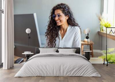 Shot of a young businesswoman working on a computer in an office. Portrait of an successful young creative businesswoman using PC at her workplace in the modern office Wall mural