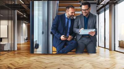 Shot of two businessmen having a discussion in an office. Teamwork, diversity and sales manager planning branding ideas with a creative designer on a tablet PC in an office. Wall mural