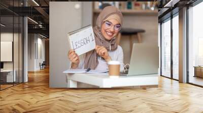 Side view head shot smiling mixed race lady freelancer wearing headset, communicating with client via video computer call. Muslim pleasant professional female tutor giving online language class Wall mural