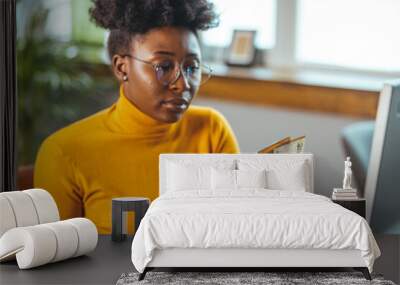 Single young african housewife with many debts feeling stressed, calculating finances, sitting at table with papers, trying to make both ends meet, not able to pay off bills Wall mural