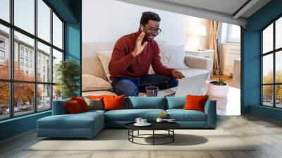 Smiling african American millennial man in glasses look at camera waving saying hello talking on video call, happy black male vlogger in spectacles greeting with subscribers shooting video blog Wall mural