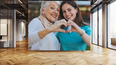 Smiling Senior Woman with Caregiver Making Heart Shape Wall mural