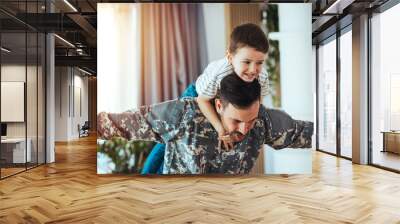 Smiling soldier reunited with his son after coming back from war. Soldier and his little son with USA flag at home. Memorial Day celebration Wall mural