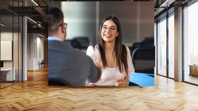 Young woman signing contracts and handshake with a manager. Shot of a young businesswoman shaking hands with a colleague in a modern office. Business people discussion advisor concept Wall mural