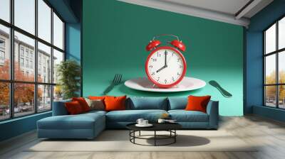 Red alarm clock pointing at 8 o'clock on white plate with fork and knife on each side on green background. Illustration of the concept of the importance of breakfast Wall mural