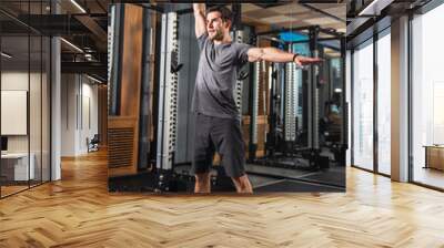 Athletic man performing kettlebell overhead press at gym Wall mural