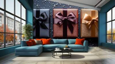 Three luxurious gift boxes wrapped in glittering paper with black, burgundy, and gold satin ribbons, set against a dark background sprinkled with silver decorations Wall mural