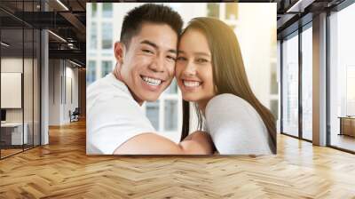 Beautiful young mixed-race couple sitting on sofa face to face and smiling at camera Wall mural