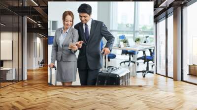 Business partners looking at the flight number on a mobile phone Wall mural