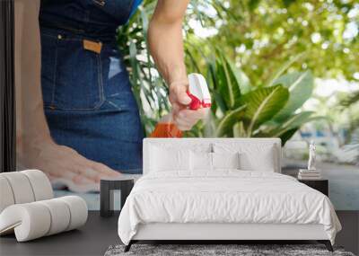 Close-up image of cafe worker spraying detergent on cafe table to wipe off dirt and bacteria Wall mural