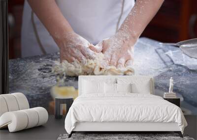 Close-up view of anonymous woman kneading cookie dough on kitchen table covered with flour Wall mural