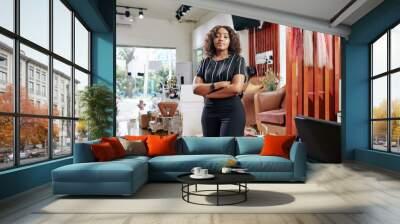 Confident attractive young Black woman standing in her beauty salon with arms folded and looking at camera Wall mural