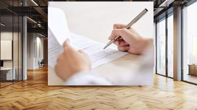 Crop shot of person with pen signing contract at desk in daylight Wall mural