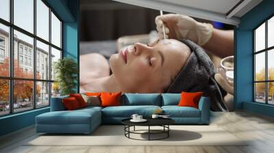 Esthetician applying glycolic acid peel on face of young woman Wall mural