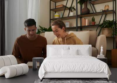 Excited young couple opening big cardboard box with shoes and clothes they ordered online Wall mural