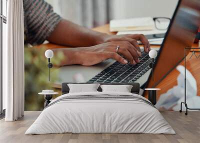 Faceless shot of modern black businesswoman working on laptop and typing on keyboard at table in office Wall mural