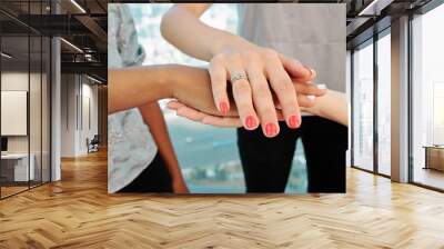 Hands of young female entrepreneurs stacking hands to express unity and cooperation Wall mural