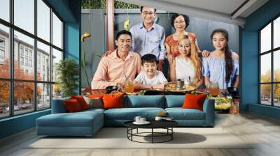 Happy big Vietnamese family posing at big dinner table for photo on smartphone Wall mural