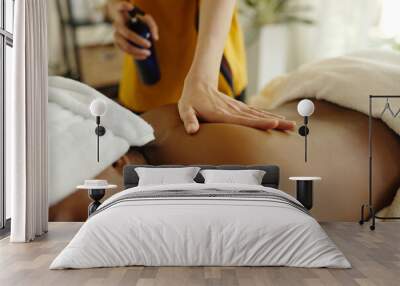 Person lying on massage table with white towel while receiving a relaxing massage using essential oils in warm indoor setting with calming ambiance Wall mural