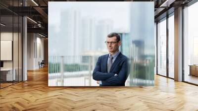 Portrait of confident mature businessman standing with arms folded outside office building Wall mural