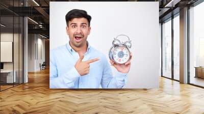 Shocked man standing on white background and pointing at alarm clock because its deadline Wall mural