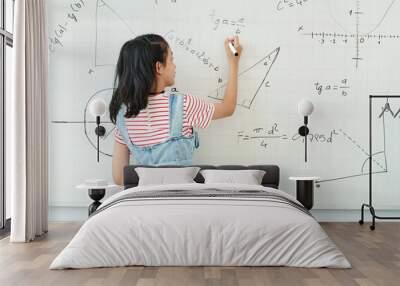 Smart schoolgirl writing on whiteboard when solving geometry task in class, view from the back Wall mural