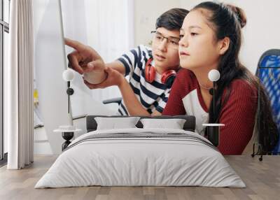 Smart teenage boy in glasses explaining part of programming code to his classmate when they are working on project Wall mural