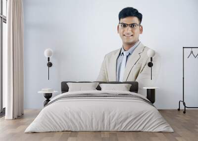 Studio portrait of smiling confident Indian businessman in suit folding arms and looking at camera Wall mural