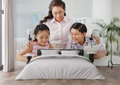 two children and their teacher reading information on tablet computer Wall mural