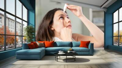 Young woman putting eye drops Wall mural