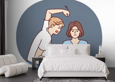 Aggressive man beats woman with violence because of jealousy and suspicion of infidelity or desire to get divorce. Nervous guy swinging his fist at girlfriend for domestic violence concept Wall mural