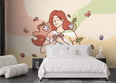 Happy woman puts hands on chest standing among flying butterflies and petals symbolizing spring mood. Cheerful girl experiences positive emotions and good mood thanks to onset of spring Wall mural