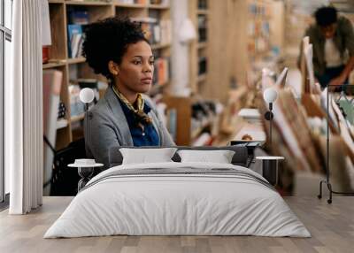 African American woman using desktop PC while working at bookstore. Wall mural