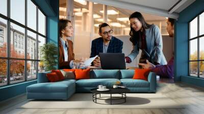 Asian CEO using laptop with colleagues during business meeting in office. Wall mural