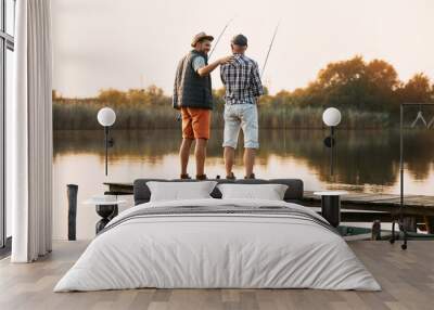 Back view of happy man and his senior father enjoy in freshwater fishing. Wall mural