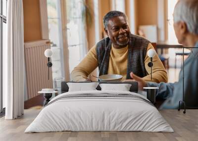 Black senior man talks to his friend during lunch at residential care home. Wall mural