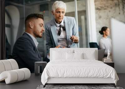 Business colleagues collaborate while working on laptop in office. Wall mural