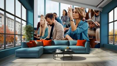 Businesswoman raising hand to ask question attending seminar in conference hall. Wall mural