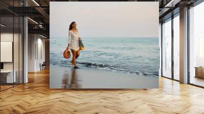 Carefree woman walking along the shore. Wall mural