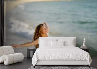 Carefree woman with arms outstretched standing at the shore. Wall mural