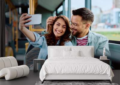 Cheerful couple taking selfie while riding in city bus. Wall mural