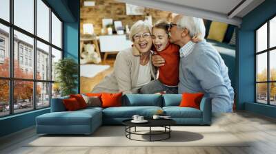 Cheerful grandparents and granddaughter having fun together at home. Wall mural