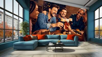 Cheerful man and his friends toast with beer while gathering in bar. Wall mural