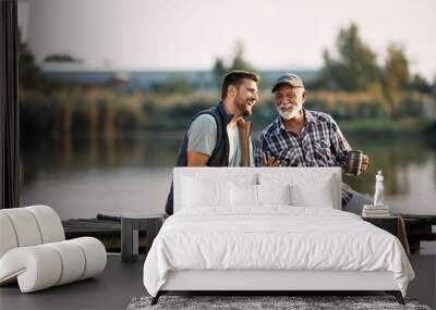 Cheerful man and his senior father have fun while fishing from pier. Wall mural