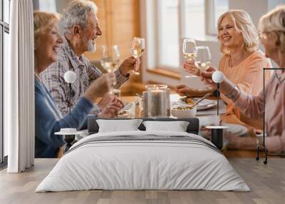 Cheerful mature people toasting with wine while having lunch at home. Wall mural