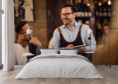 Cheerful waiter communicating with customers while taking their orders on touchpad. Wall mural